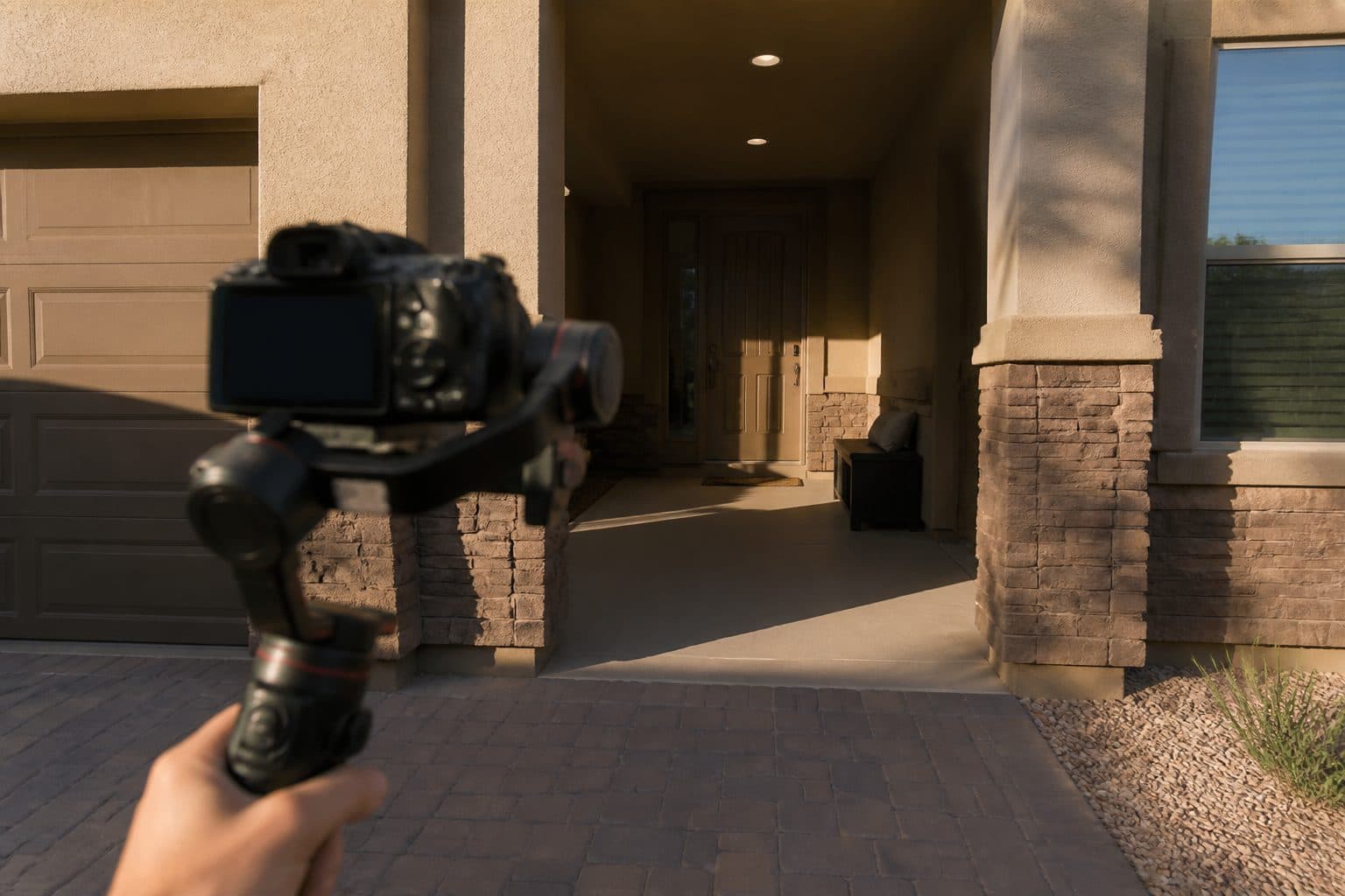Handheld camera filming a zero-step front entry with a covered landing, late-day Nevada light.
