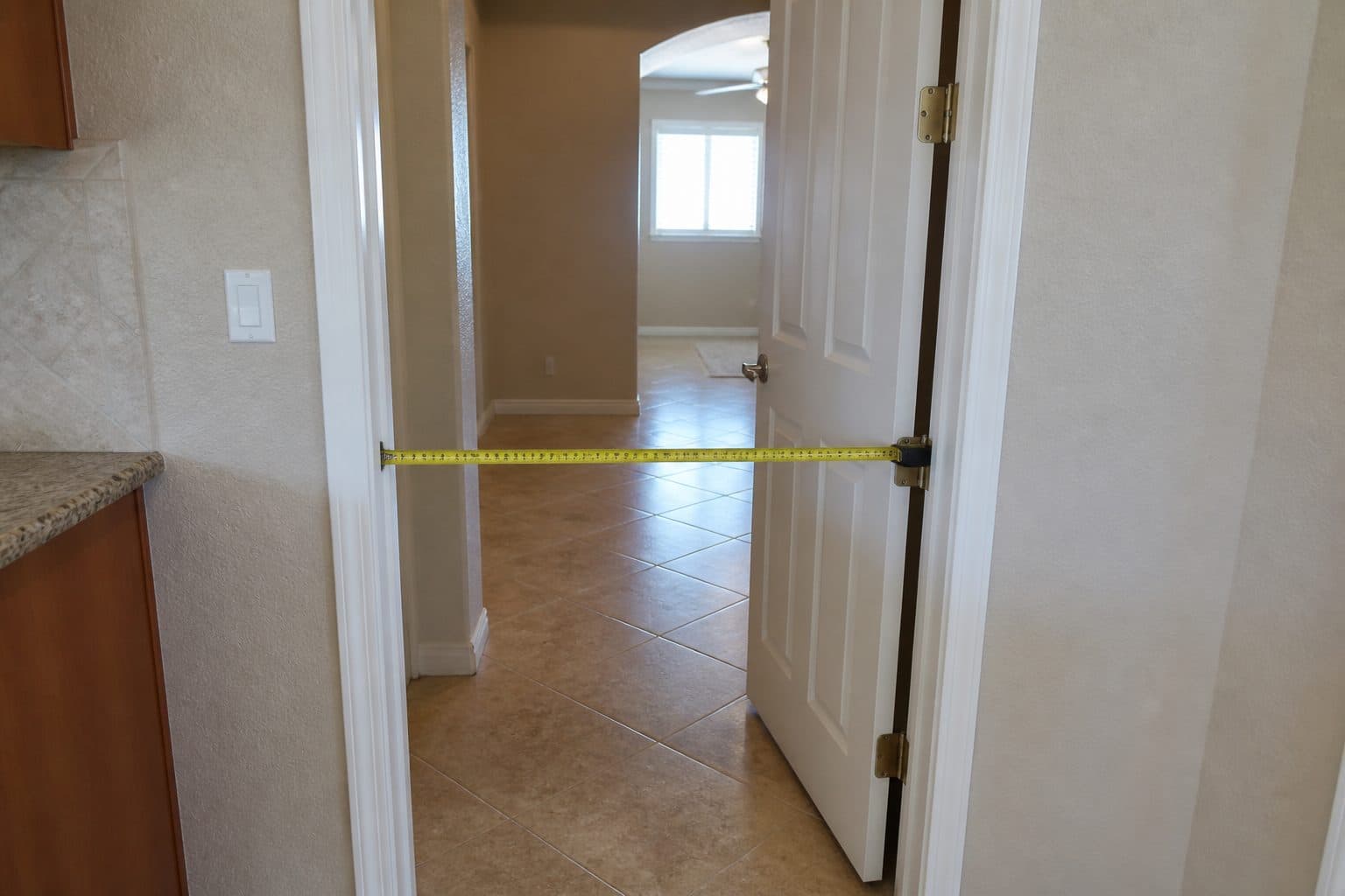 Interior doorway with a tape measure showing roughly 36 inches of clear width in a single-level home.